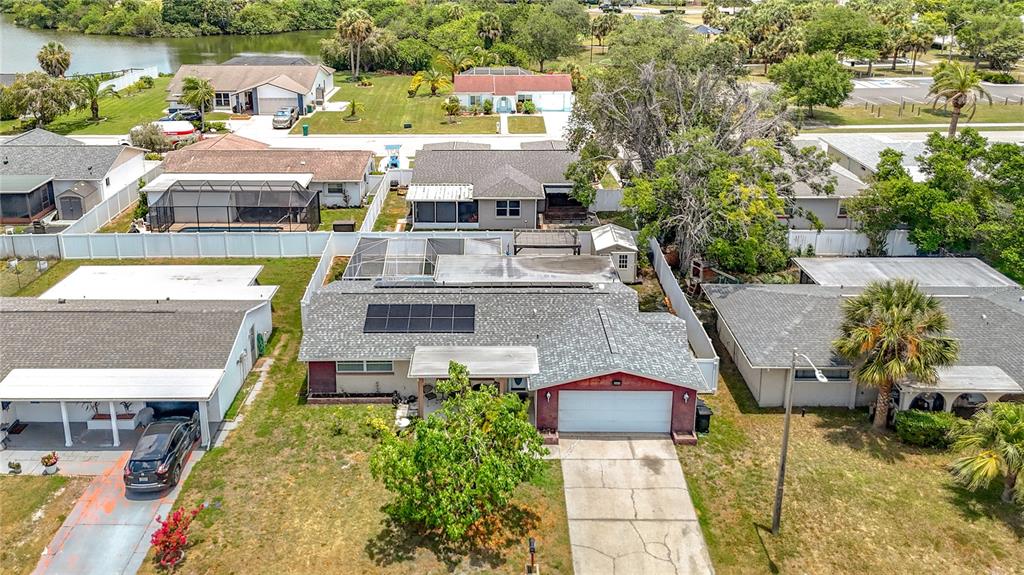 An aerial view shows a suburban house with solar panels, a garage, and a pool — 8944 LEDGESTONE LANE, PORT RICHEY, FL