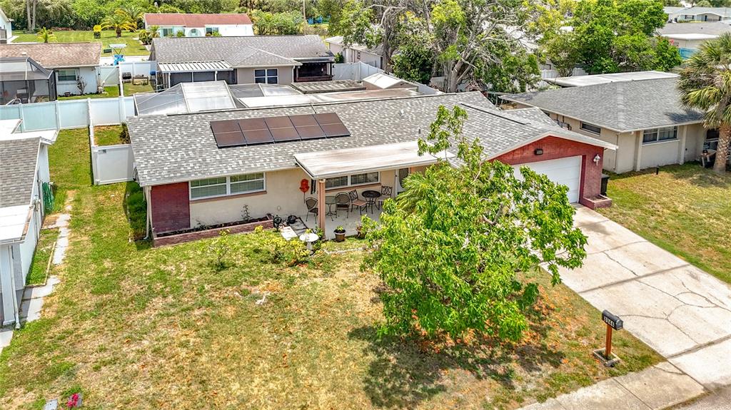 An aerial view shows a single-story house with solar panels, a carport, and a lawn — 8944 LEDGESTONE LANE, PORT RICHEY, FL