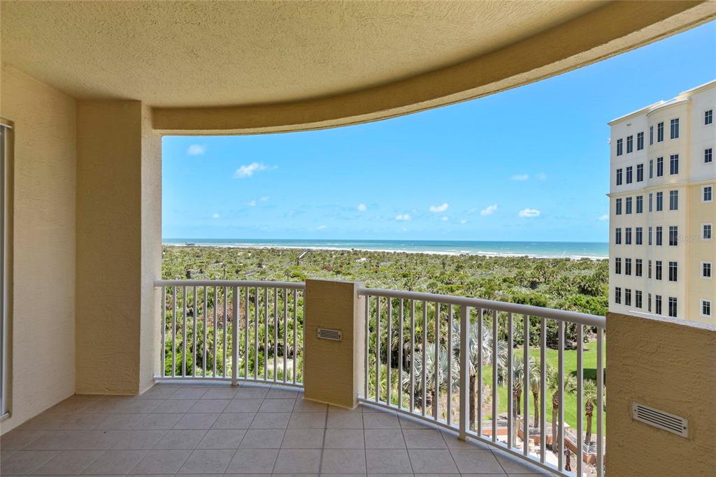 A tiled balcony overlooks a coastal landscape with a view of the ocean and nearby buildings — 261 MINORCA BEACH WAY UNIT 606, NEW SMYRNA BEACH, FL