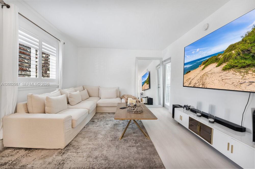 A bright living room features a large sectional sofa, a coffee table, and a wall-mounted television — 240 Galen Dr # 112, Key Biscayne FL 33149, KEY BISCAYNE, FL