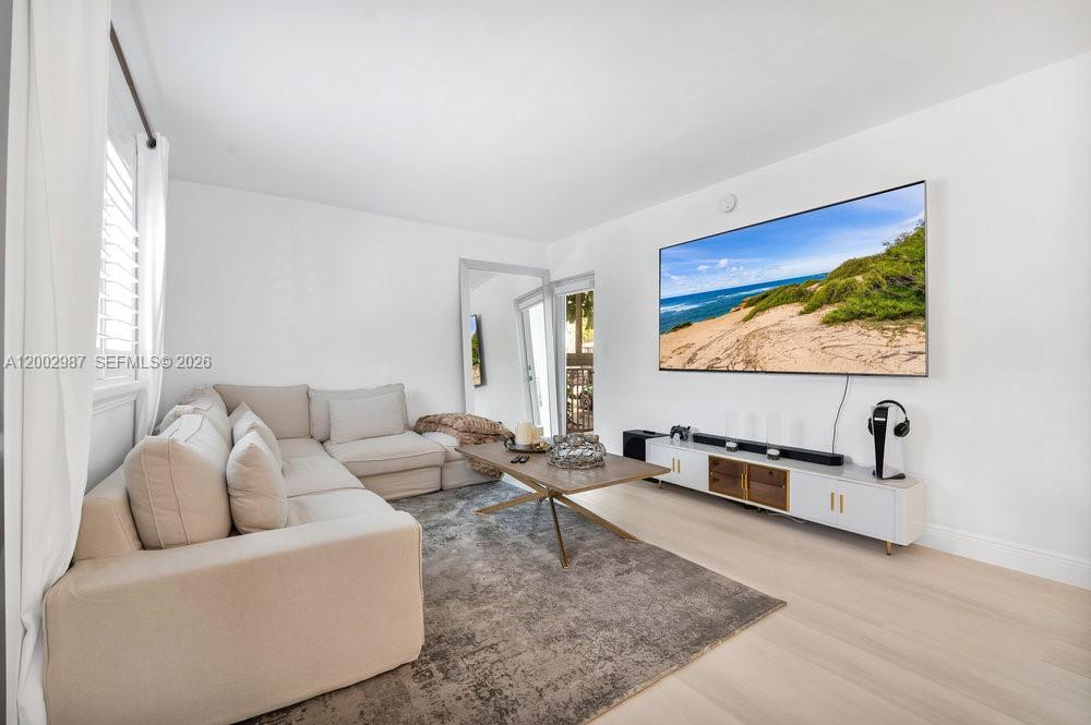 A living room features a large sectional sofa, a coffee table, and a wall-mounted television — 240 Galen Dr # 112, Key Biscayne FL 33149, KEY BISCAYNE, FL