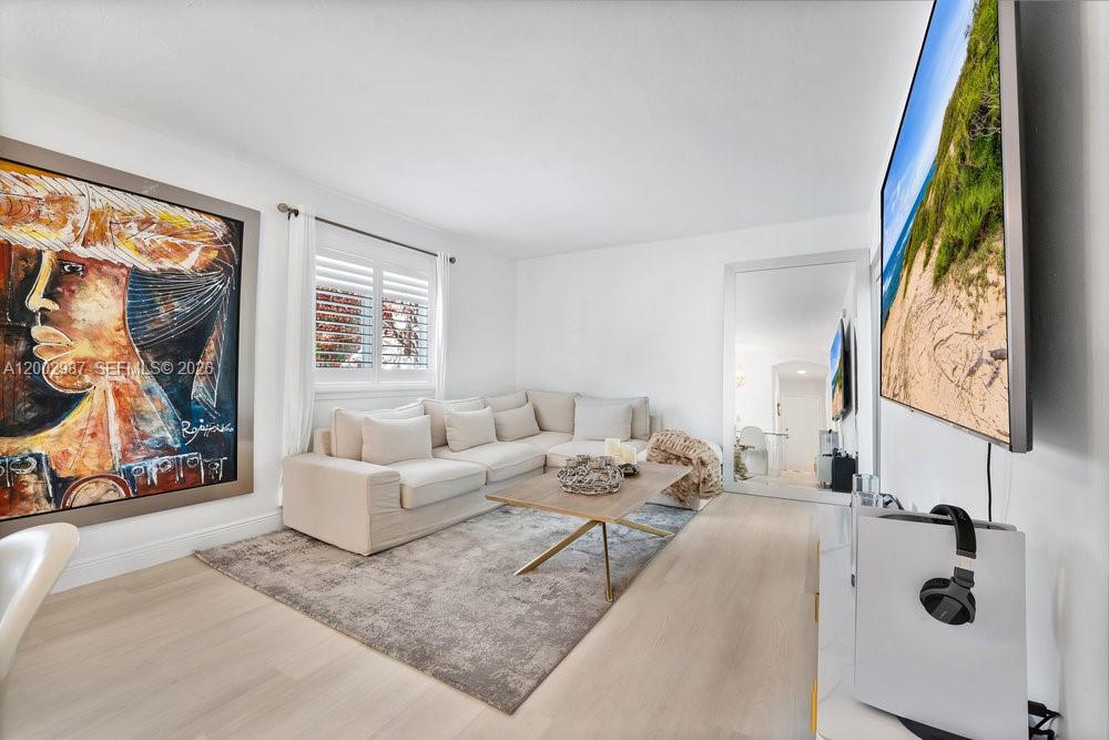 A living room features a beige sectional sofa, a coffee table, and large wall art — 240 Galen Dr # 112, Key Biscayne FL 33149, KEY BISCAYNE, FL