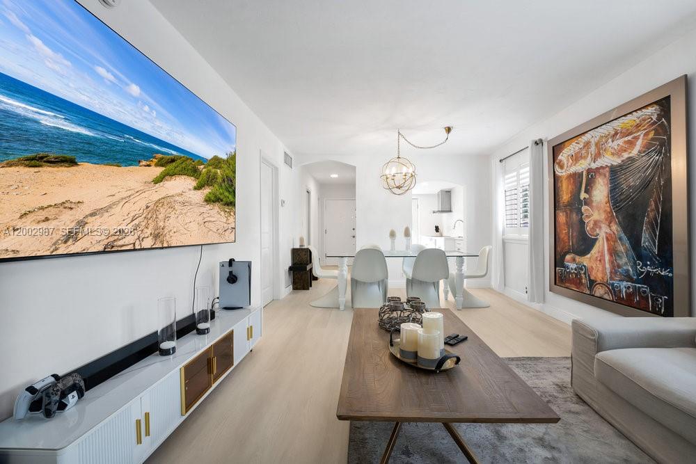A living and dining area with light wood floors, a large television, and modern furniture — 240 Galen Dr # 112, Key Biscayne FL 33149, KEY BISCAYNE, FL