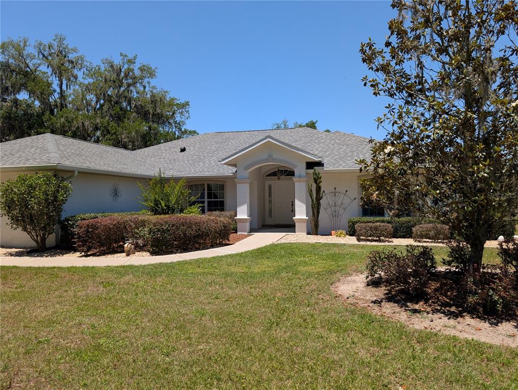 A single-story house with a white stucco exterior, a gray shingled roof, and a front entryway — 999 NE 120 PLACE, OCALA, FL