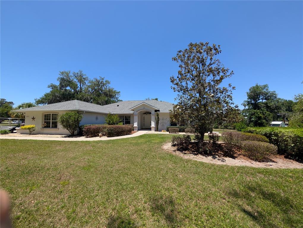A single-story house with a light-colored exterior, a gray roof, and a landscaped front yard — 999 NE 120 PLACE, OCALA, FL