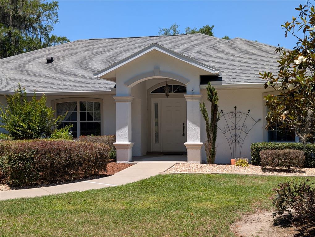 The front exterior of a single-story house features a covered entryway with white columns — 999 NE 120 PLACE, OCALA, FL