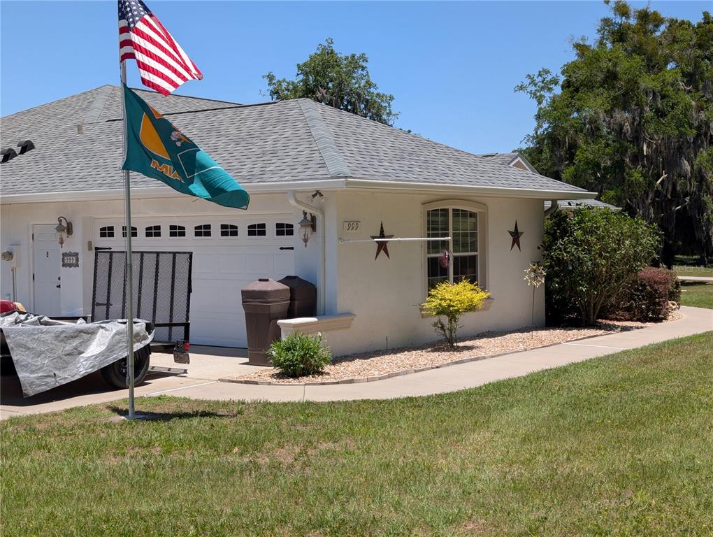 A single-story house exterior features a white garage, a flag pole, and decorative wall stars — 999 NE 120 PLACE, OCALA, FL