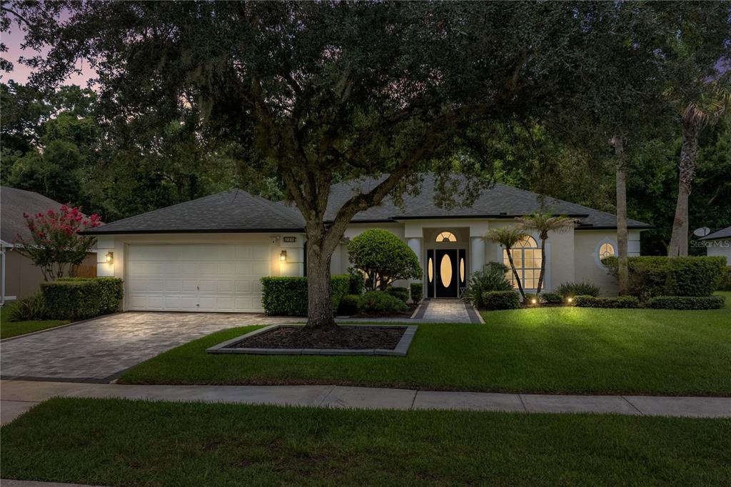 A single-story house with a white garage, arched entryway, and a large tree in front — 223 BLUE CREEK DRIVE, WINTER SPRINGS, FL