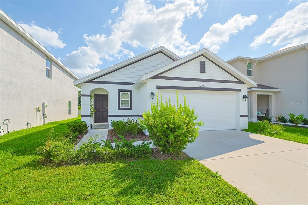 A single-story house with a white exterior, a two-car garage, and a front lawn — 12136 LILY MAGNOLIA LANE, RIVERVIEW, FL