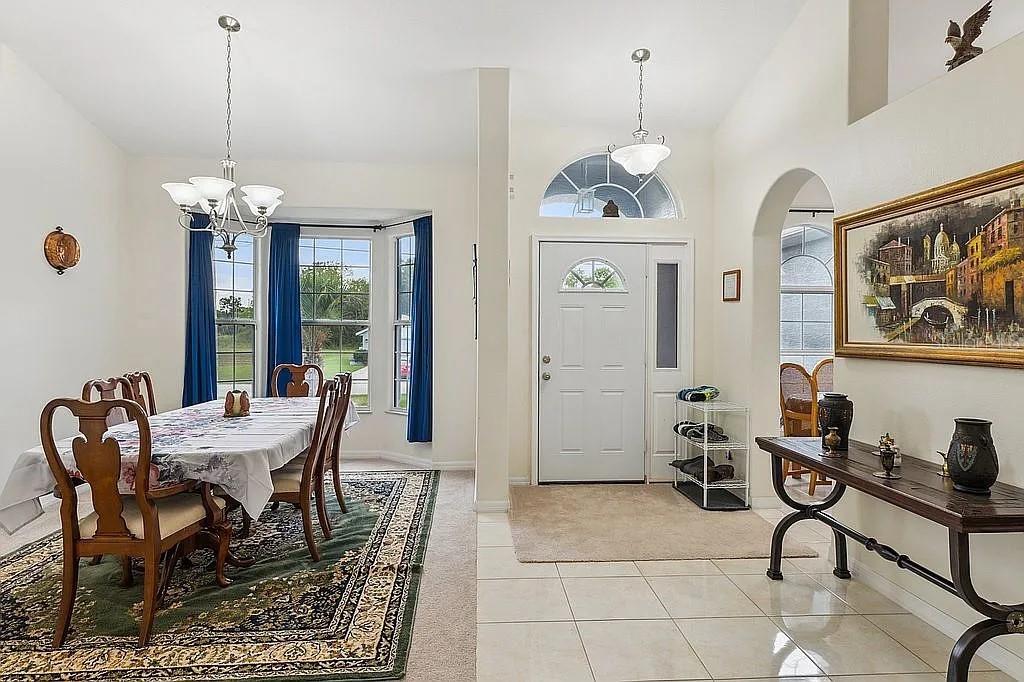 A dining area with a patterned rug sits beside an entryway featuring tile floors — 8628 SW 133RD LANE ROAD, OCALA, FL