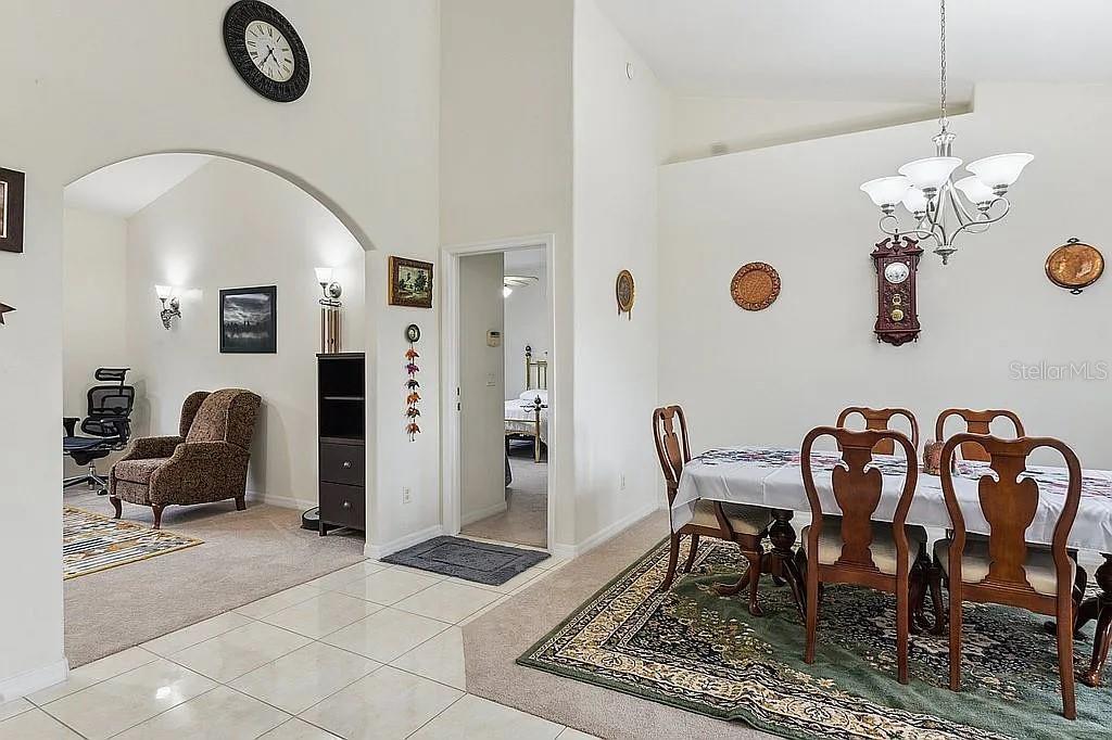 A dining area with a table and chairs sits adjacent to a carpeted living space — 8628 SW 133RD LANE ROAD, OCALA, FL