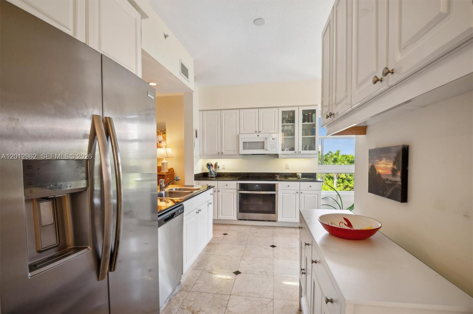 A kitchen features white cabinets, stainless steel appliances, dark countertops, and light tile flooring — 701 Crandon Blvd # 1, Key Biscayne FL 33149, KEY BISCAYNE, FL