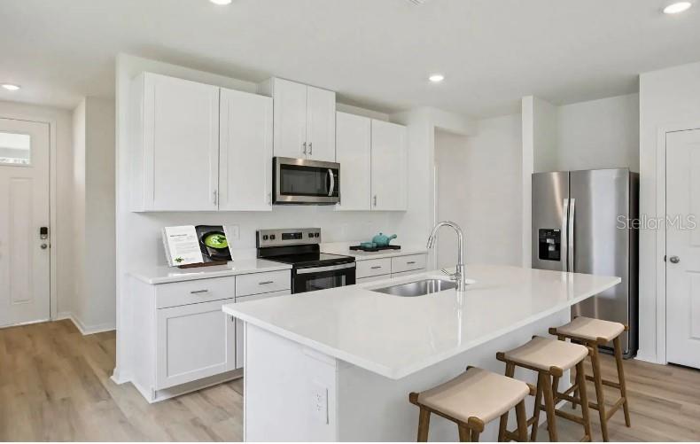 A modern kitchen features white cabinets, stainless steel appliances, and a large central island — 153 CANOE BEND AVENUE, NOKOMIS, FL