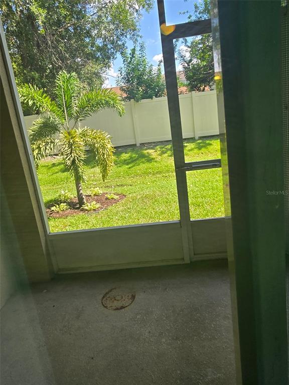 A screened-in concrete patio overlooks a grassy backyard with a palm tree and white fence — 2157 BROADWAY VIEW AVENUE, BRANDON, FL