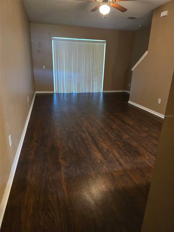An empty room features dark wood-look flooring, tan walls, and a sliding glass door — 2157 BROADWAY VIEW AVENUE, BRANDON, FL