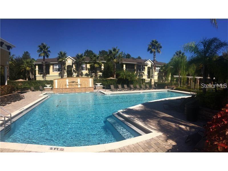 A swimming pool with a fountain feature sits in front of a multi-story apartment building — 10019 COURTNEY PALMS BOULEVARD UNIT 201, TAMPA, FL