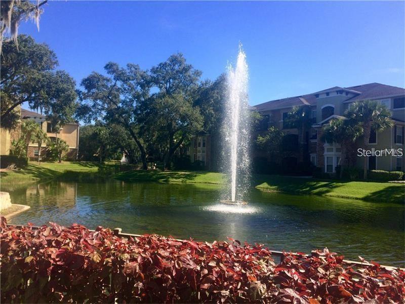 A fountain sprays water in a pond surrounded by apartment buildings and landscaping — 10019 COURTNEY PALMS BOULEVARD UNIT 201, TAMPA, FL