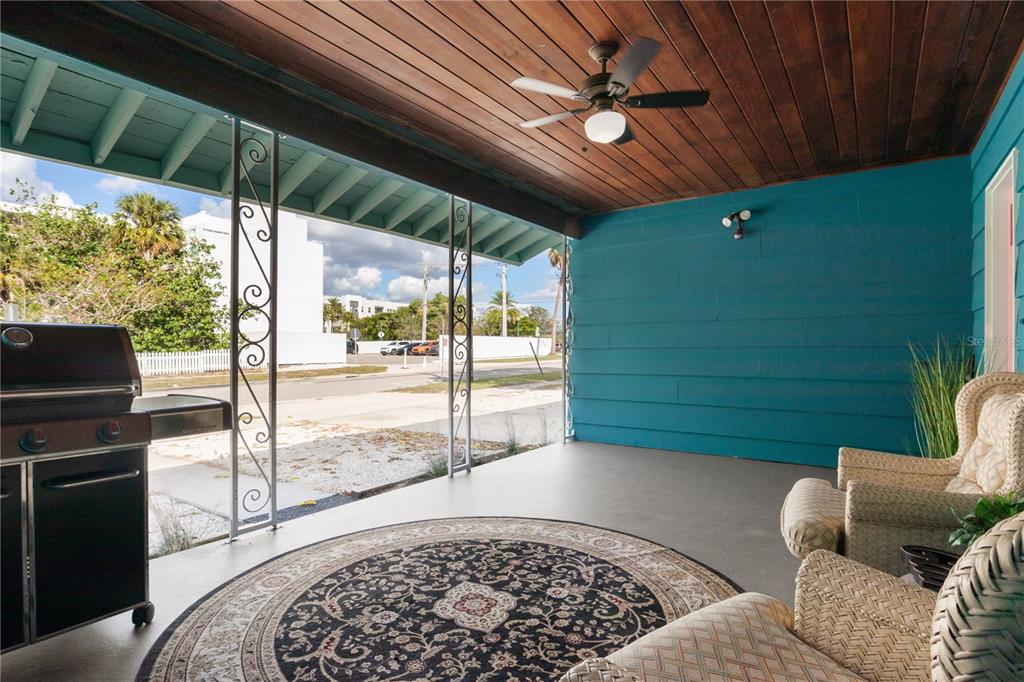 A covered patio features a wood-paneled ceiling, teal walls, a ceiling fan, and wicker furniture — 1270 5TH STREET, SARASOTA, FL