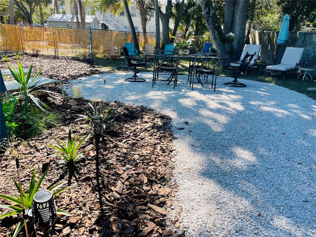 A backyard features a white shell patio with outdoor furniture, mulch beds, and small plants — 1270 5TH STREET, SARASOTA, FL