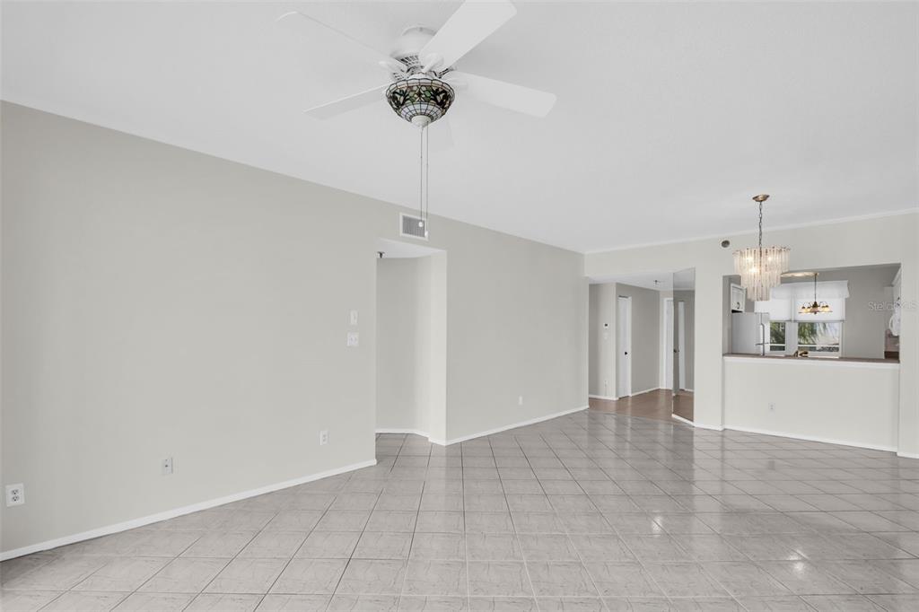 An open-concept living area features light gray walls, white tile flooring, and a ceiling fan — 7932 SAILBOAT KEY BOULEVARD S UNIT 402, SOUTH PASADENA, FL