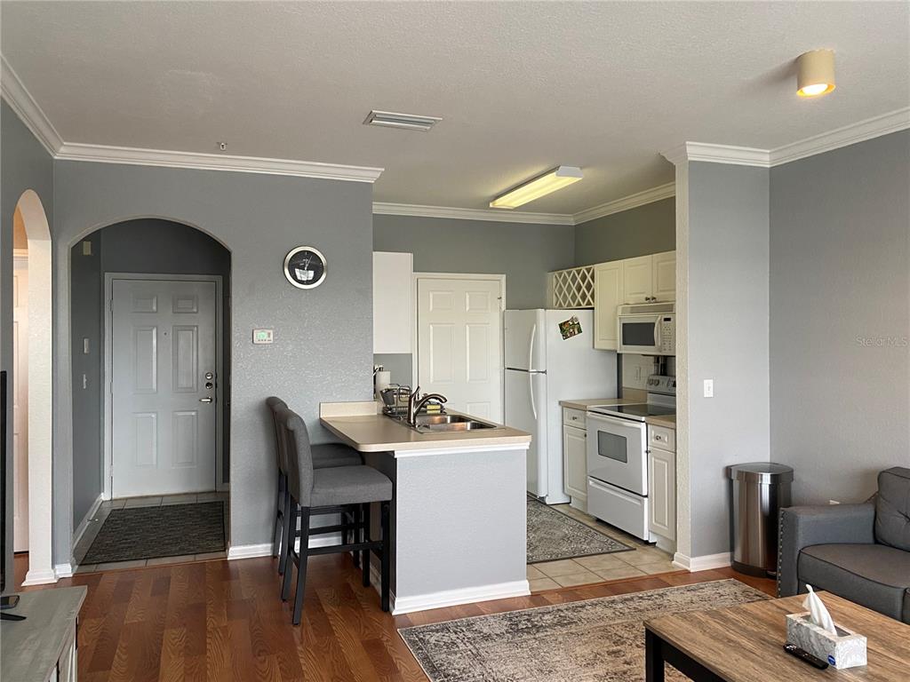 A kitchen with white cabinets and appliances features a breakfast bar and gray walls — 1216 S MISSOURI AVENUE UNIT 418, CLEARWATER, FL