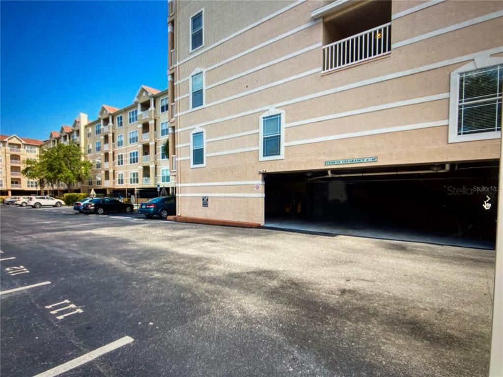 An exterior view shows a multi-story apartment building with a ground-level covered parking garage — 1216 S MISSOURI AVENUE UNIT 418, CLEARWATER, FL