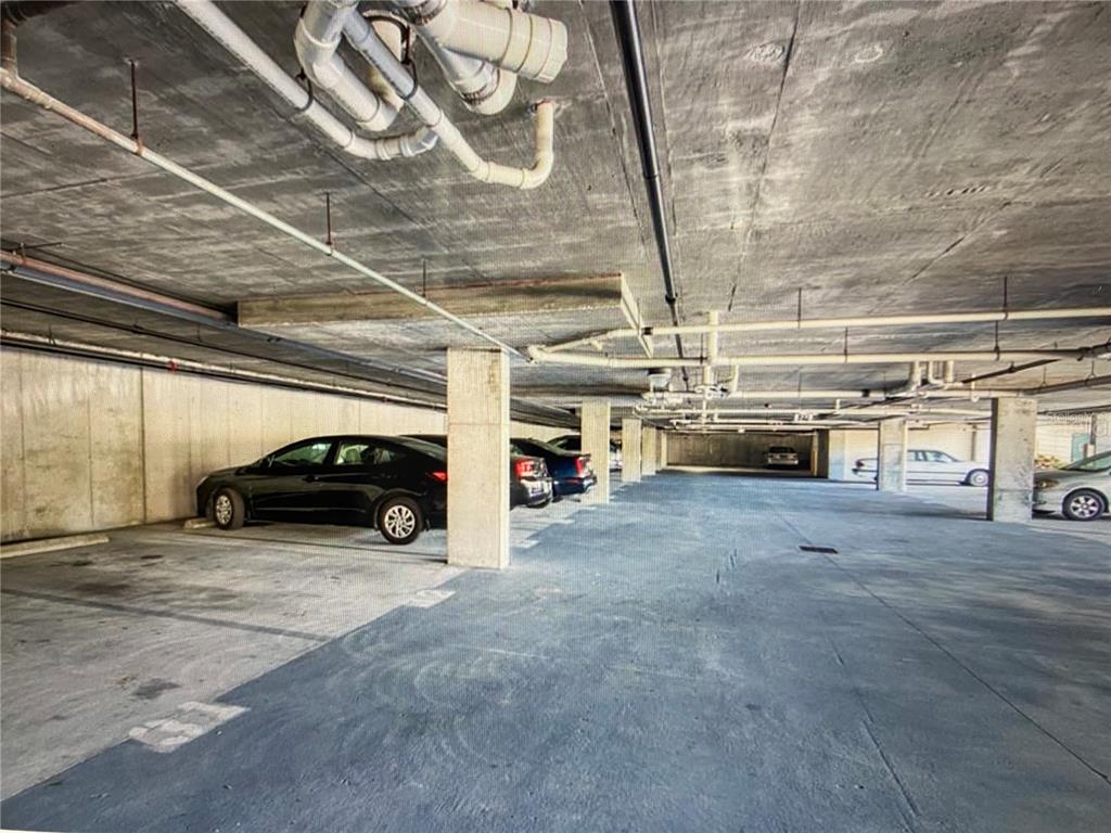 A concrete parking garage features support pillars, exposed overhead pipes, and several parked cars — 1216 S MISSOURI AVENUE UNIT 418, CLEARWATER, FL