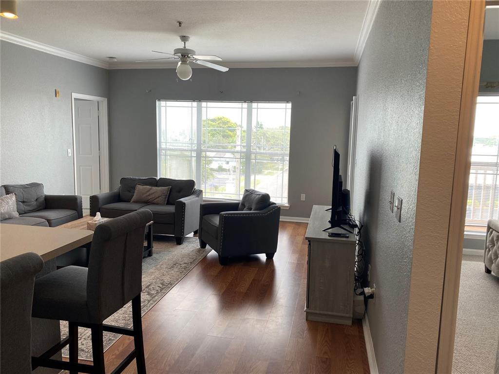 A living room with gray walls, wood-look flooring, a ceiling fan, and gray furniture — 1216 S MISSOURI AVENUE UNIT 418, CLEARWATER, FL