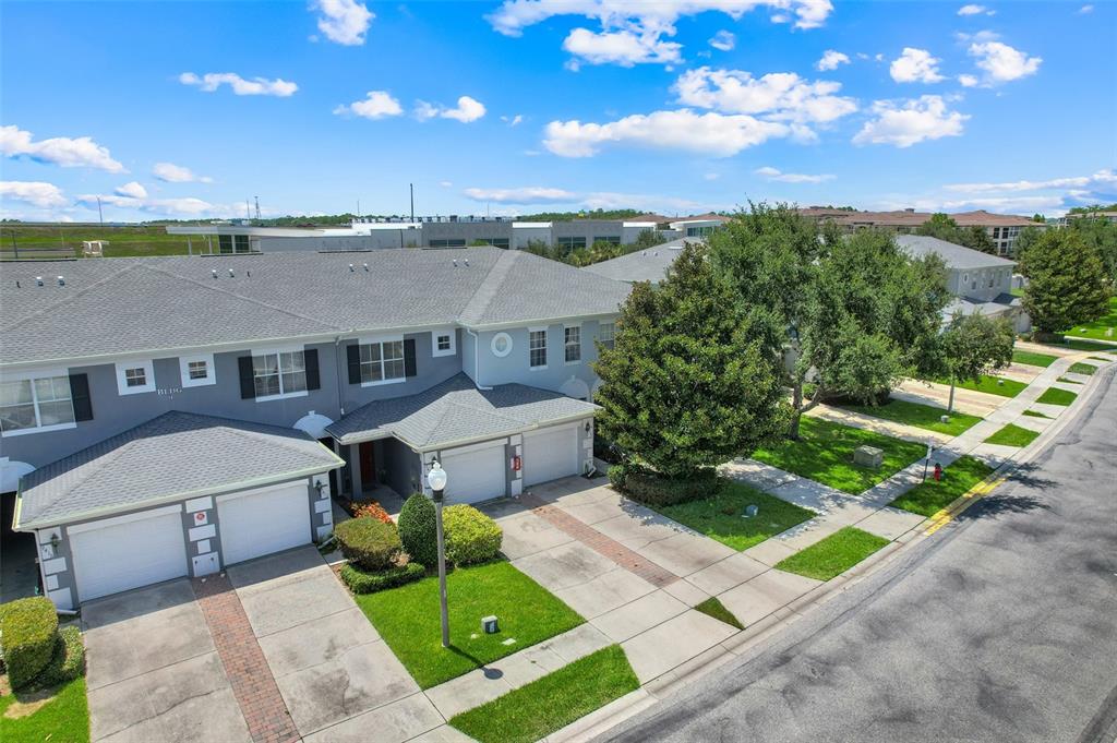 An aerial view of a two-story townhouse complex with attached garages and landscaped front yards — 9408 FLOWERING COTTONWOOD ROAD, ORLANDO, FL