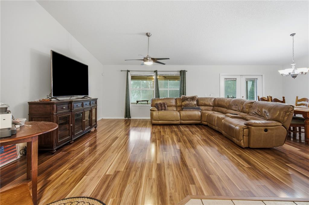 A living room features wood flooring, a large sectional sofa, and a television on a console — 16723 SE 173RD TERRACE ROAD, WEIRSDALE, FL