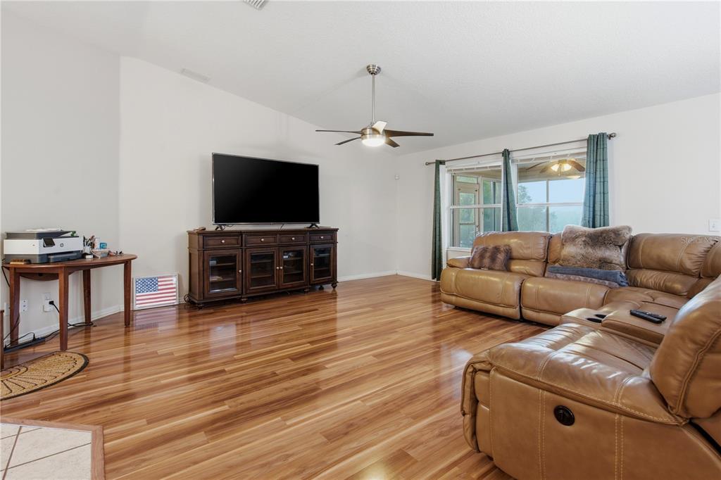 A living room features hardwood floors, a large sectional sofa, and a television console — 16723 SE 173RD TERRACE ROAD, WEIRSDALE, FL