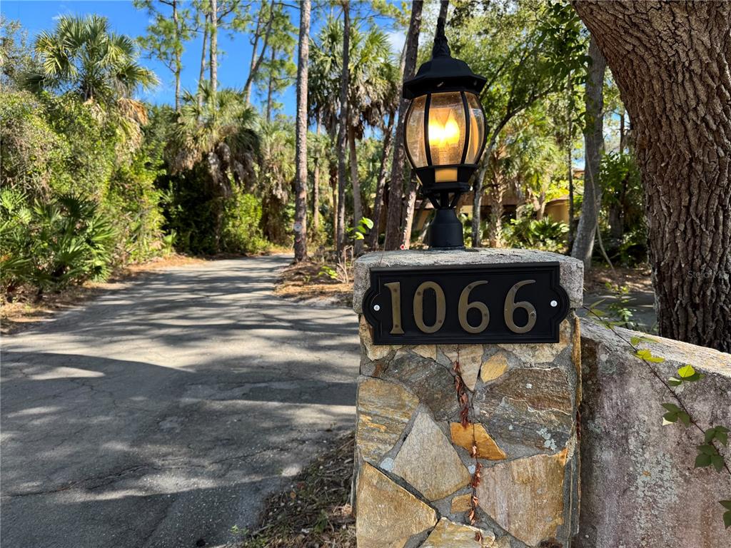 A stone pillar with a lit lamp and house number stands beside a paved driveway — 1066 CONOVER STREET, PORT CHARLOTTE, FL