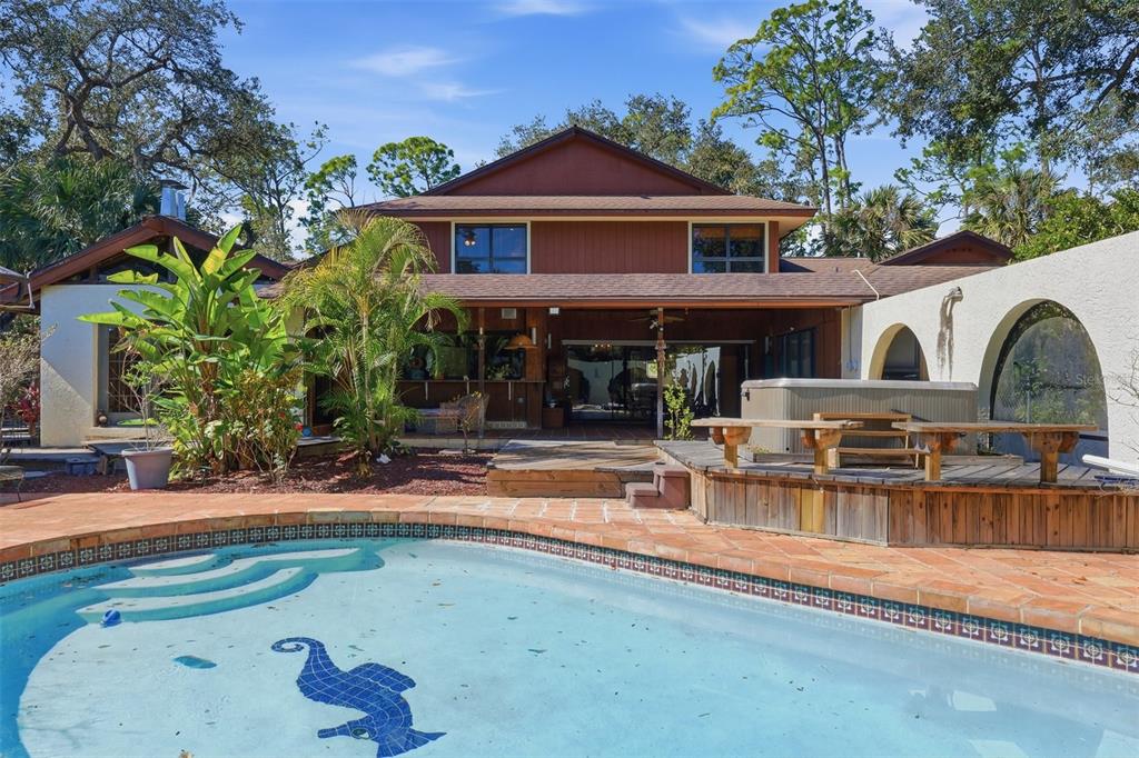 A backyard view of a two-story house with a swimming pool and a wooden deck — 1066 CONOVER STREET, PORT CHARLOTTE, FL