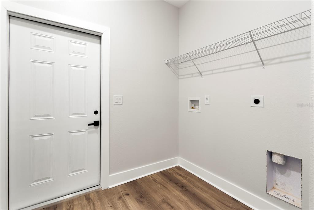 A laundry room with wood-look flooring, a white door, and wall-mounted wire shelving — 12248 SW 96TH LANE, DUNNELLON, FL