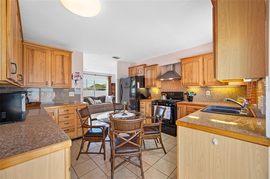 A kitchen with wooden cabinets, granite countertops, and a dining table with four chairs — 12400 PARK BLVD UNIT 623, SEMINOLE, FL