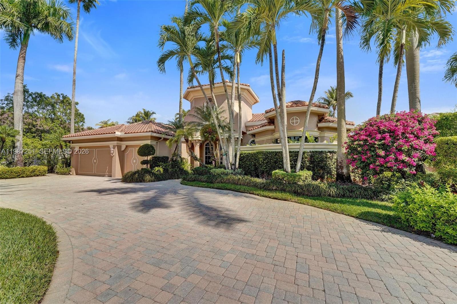 A tan stucco house with a tiled roof and a paved driveway surrounded by palm trees — 10813 Blackhawk St, Plantation FL 33324, PLANTATION, FL