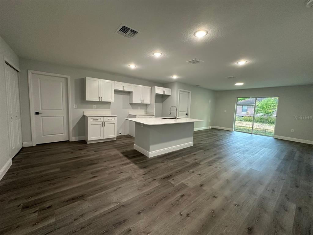 A kitchen with white cabinets, a central island, and gray wood-look flooring — 15 BAHIA COURT TRACK, OCALA, FL
