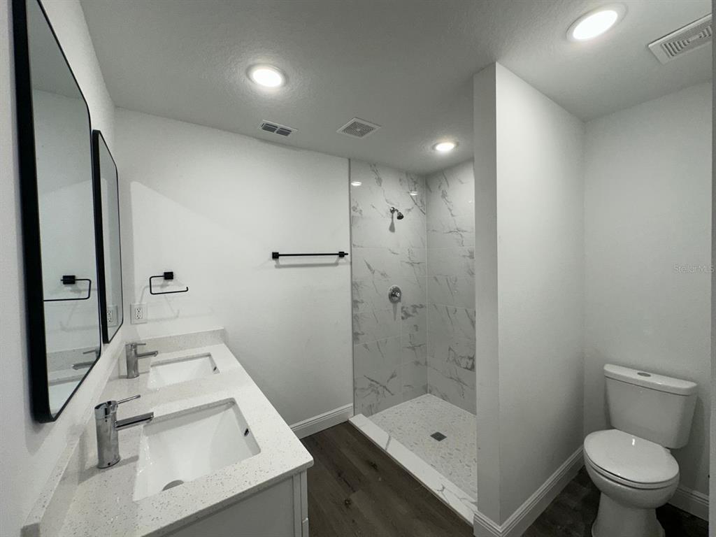 A modern bathroom features a double vanity, a walk-in tiled shower, and a toilet — 15 BAHIA COURT TRACK, OCALA, FL