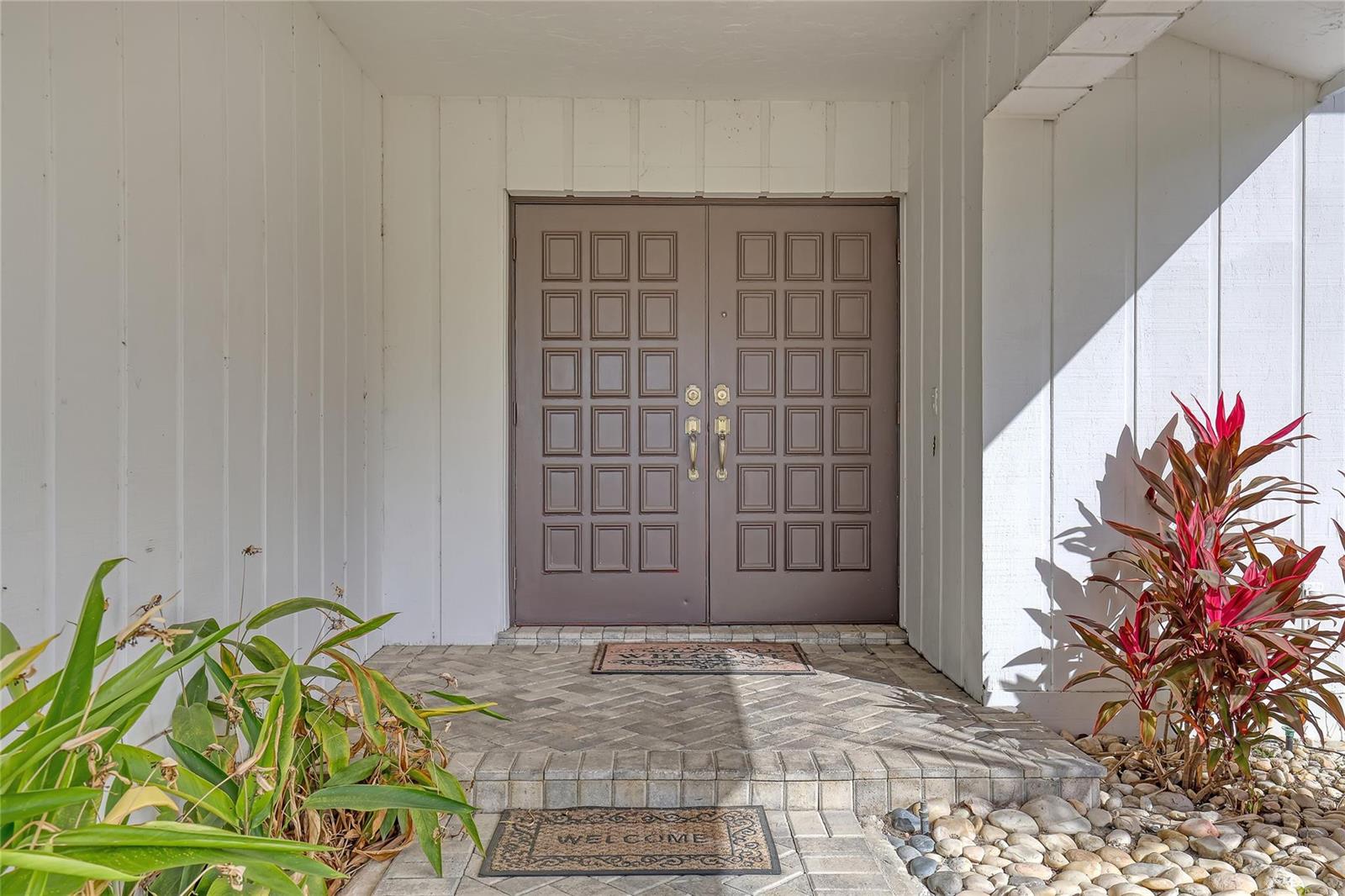 A brown double door with square panels sits at the entrance of a white house — 4989 Pineview Circle, Delray Beach FL 33445, DELRAY BEACH, FL