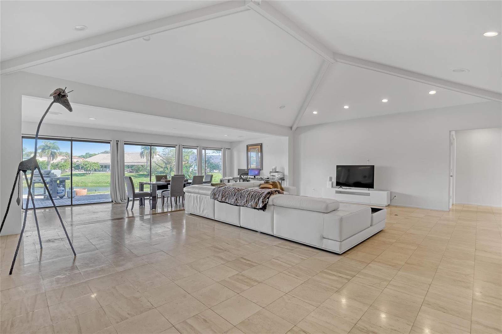 A spacious living room features a white sectional sofa, tile flooring, and a large giraffe sculpture — 4989 Pineview Circle, Delray Beach FL 33445, DELRAY BEACH, FL