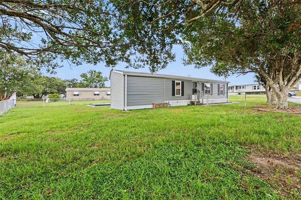 A gray mobile home sits on a grassy lot under large shade trees — 9213 SALISBURY DRIVE, BROOKSVILLE, FL
