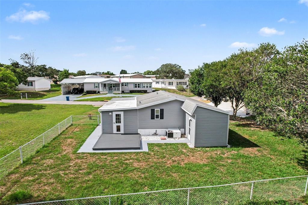 An aerial view shows a gray single-story house with a flat-roofed deck and fenced yard — 9213 SALISBURY DRIVE, BROOKSVILLE, FL
