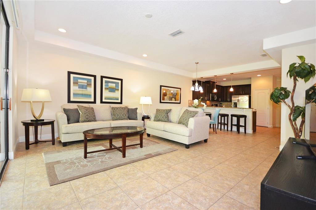 A living room with tile floors, two sofas, a coffee table, and an open kitchen — 8211 ROSEVILLE ROAD, DAVENPORT, FL