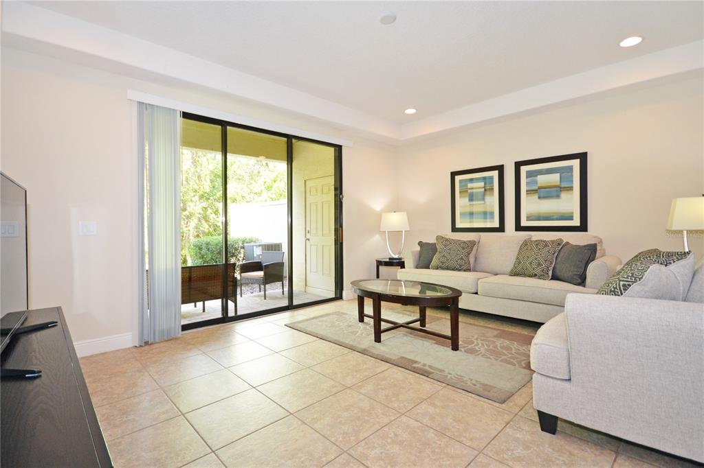 A living room features tile flooring, a beige sofa, a coffee table, and sliding glass doors — 8211 ROSEVILLE ROAD, DAVENPORT, FL