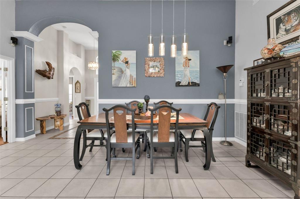A dining room features a wooden table with six chairs, blue walls, and tile flooring — 1644 PALACE COURT, PUNTA GORDA, FL