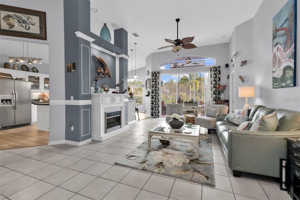 A living room features a fireplace, tile flooring, a ceiling fan, and a sliding glass door — 1644 PALACE COURT, PUNTA GORDA, FL