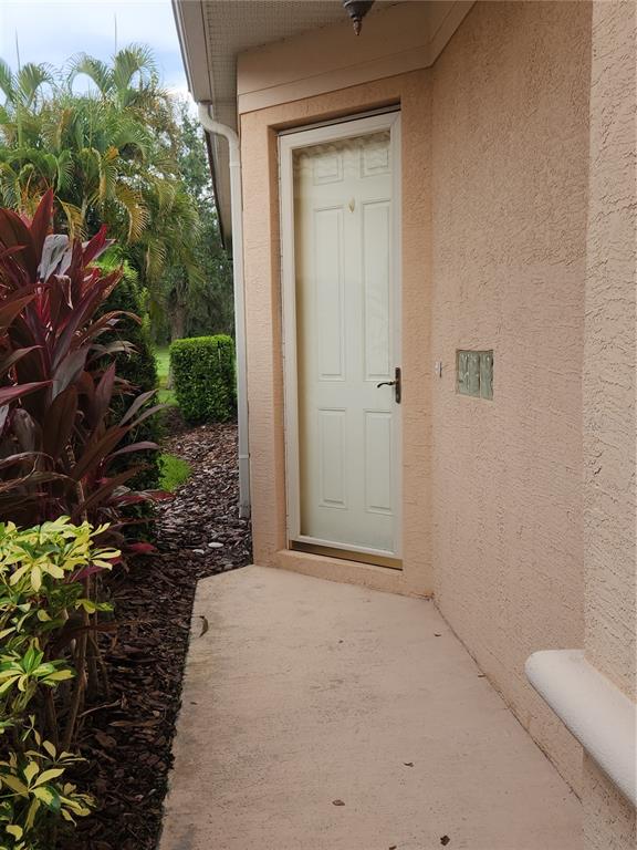 A beige exterior door with a storm door is set into a stucco wall — 6251 WINGSPAN WAY, BRADENTON, FL
