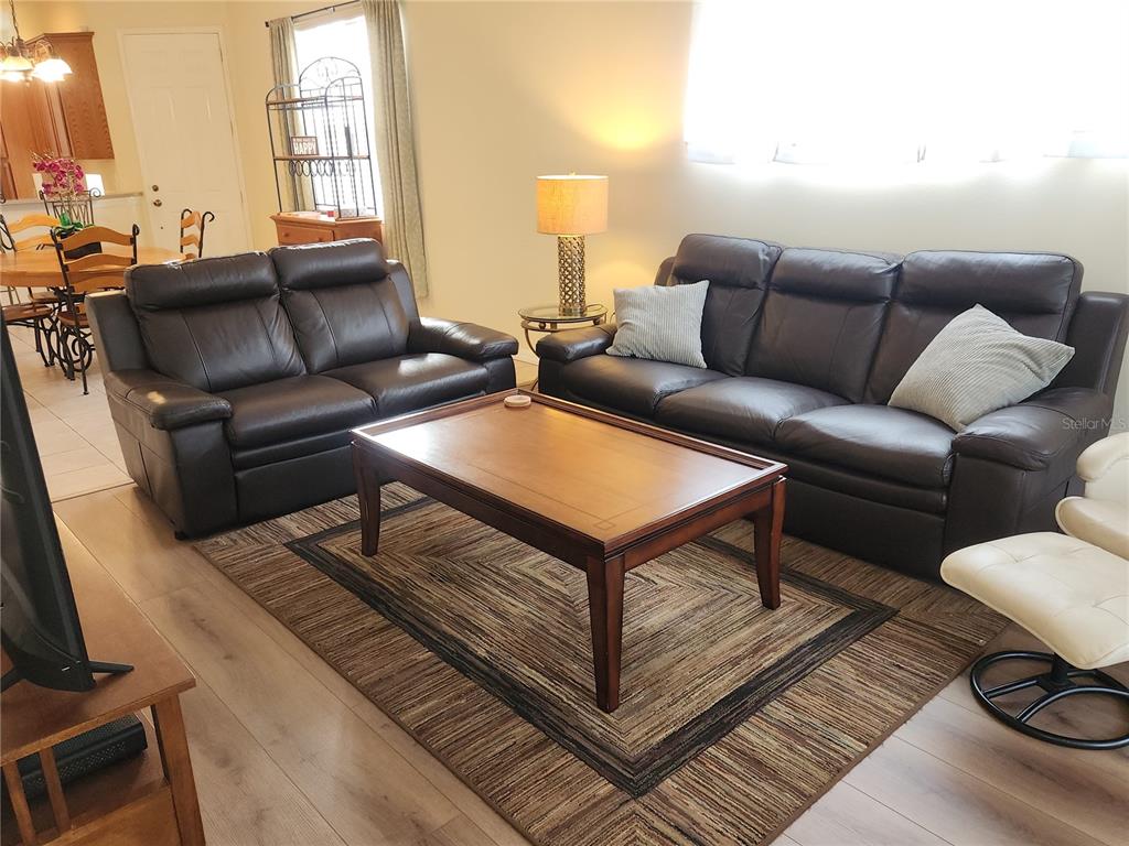 A living room features two dark leather sofas, a wooden coffee table, and a patterned rug — 6251 WINGSPAN WAY, BRADENTON, FL