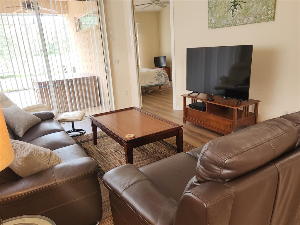 A living room with brown leather sofas, a wooden coffee table, and a television stand — 6251 WINGSPAN WAY, BRADENTON, FL