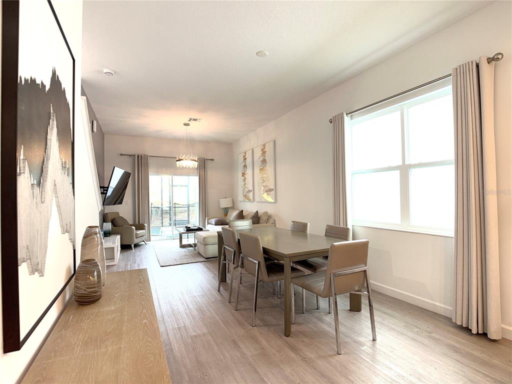 A dining area with a table and chairs leads into a living room with sliding doors — 332 FAMAGUSTA DRIVE, DAVENPORT, FL